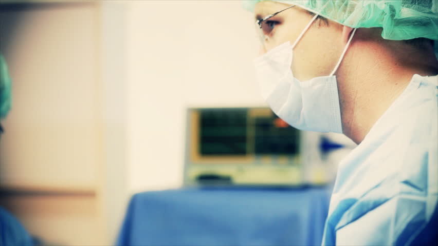 The camera dollies from a male surgeon past IV containers in the foreground two female surgeons. Tinting and vignetting added for affect.