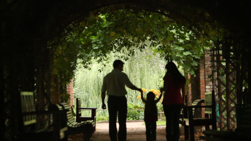 Family walks from one end of the tunnel to another in a park, silhouettes 