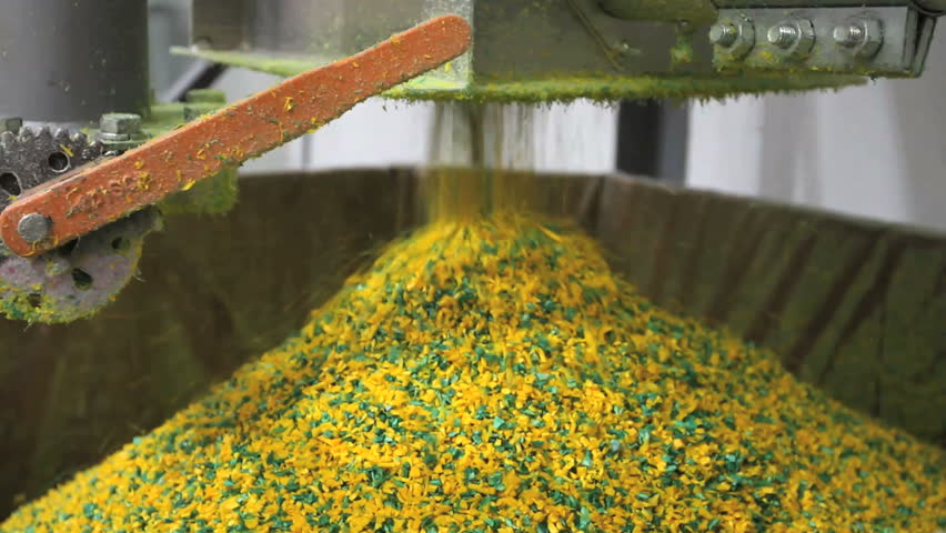 Bright yellow plastic pellets pour from a machine: 2 shots 
