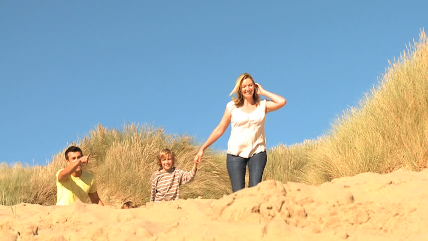 Attractive young caucasian family enjoying leisure time together on coastal sand dunes  filmed at 60FPS