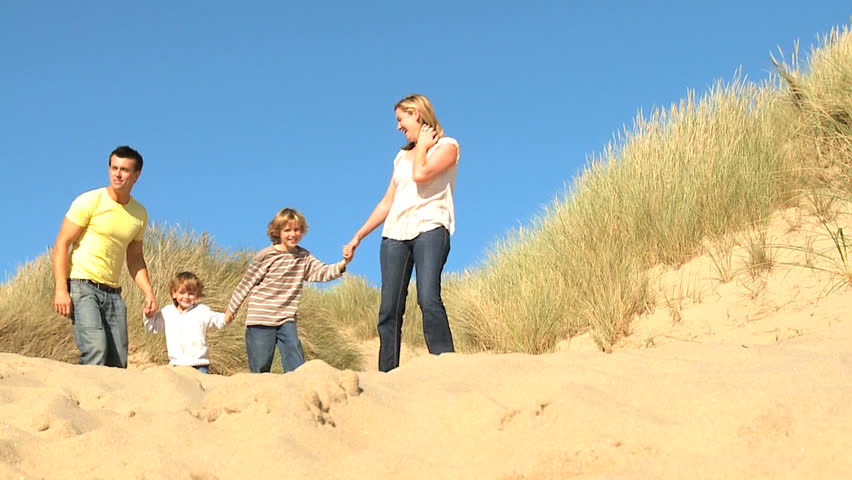 Attractive young caucasian family enjoying leisure time together on coastal sand dunes  filmed at 60FPS
