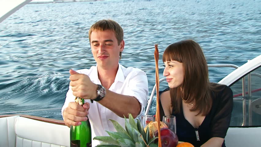 Celebrating on a yacht. Two lovers kissing and drinking champagne on board the yacht.