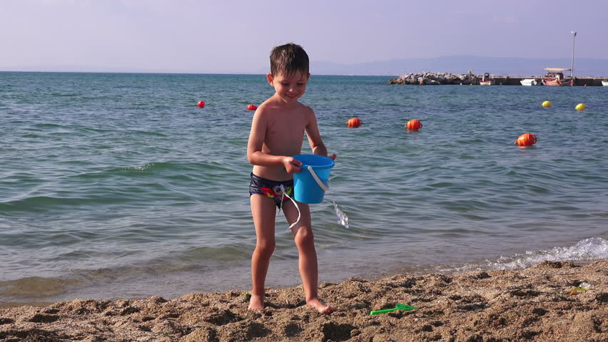 Little boy holding a bucket and playing on the beach. | Photo:Shutterstock