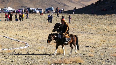 Ulgii Mongolia October 6 2018 Kazakh Eagle Hunter In The Traditional Clothing With The Well Trained Eagles On His Hand Riding Horseback At The Golden Eagle Festival In Ulgii Mongolia