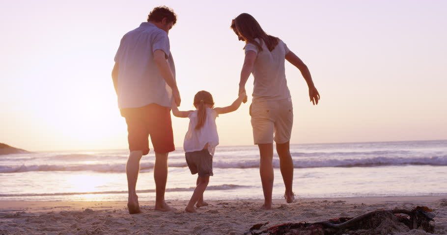 Happy family on the beach holding hands swinging little girl around at sunset on vacation slow motion RED DRAGON