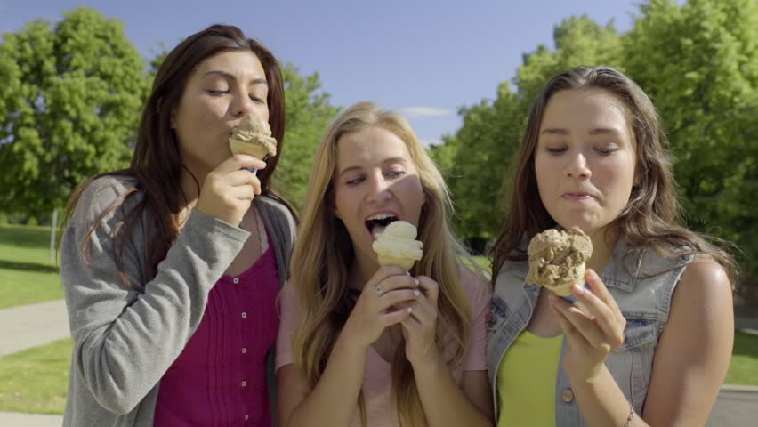 Teen Girls Go For A Walk In The Park Enjoy Eating Ice Cream Cones On