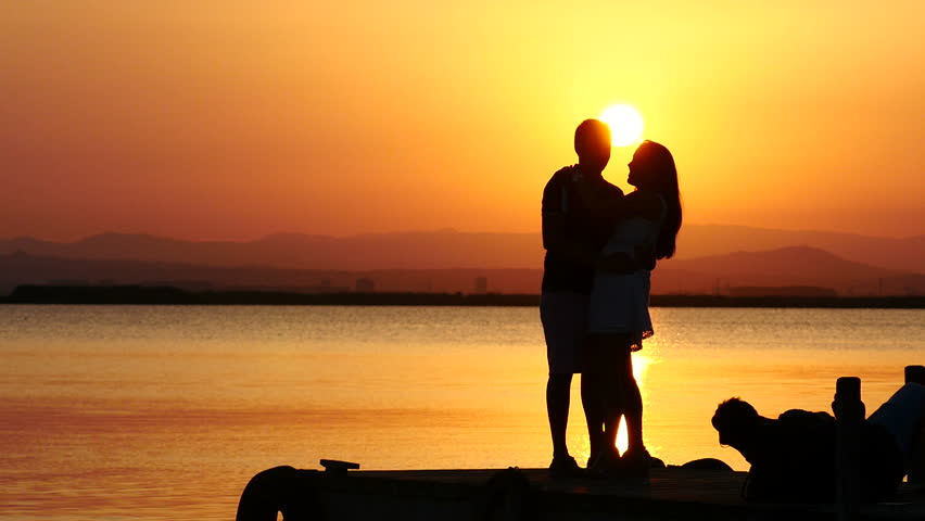 Romantic Couple Walks Towards Sunset Holding Hands Stock