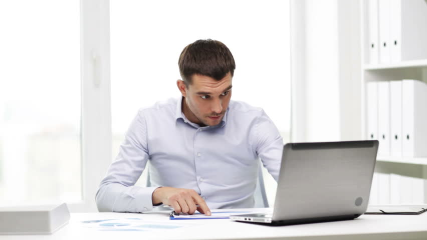 Happy Young Businessman Reading Paperwork At Desk In Office. Casual Man ...