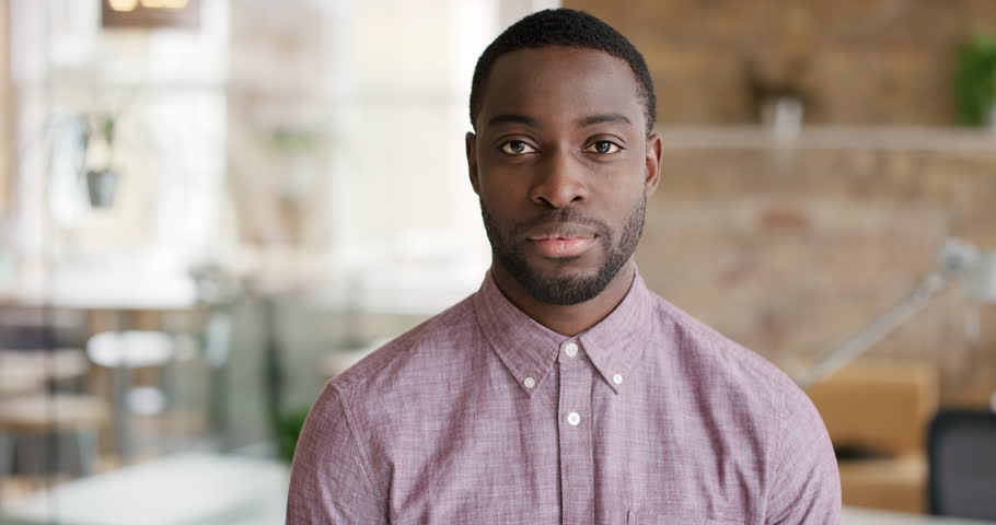 Portrait of successful African American Businessman entrepreneur working at busy office smiling