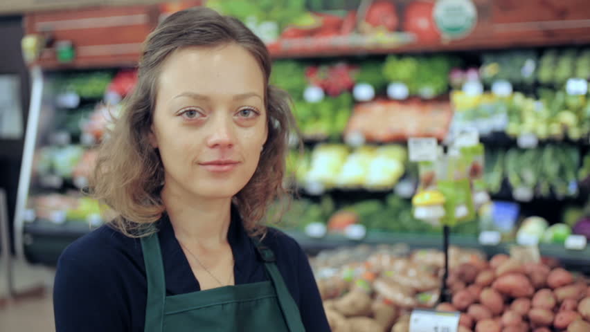 Portrait Of A Grocery Store Clerk In Front Of A Vegetable Section Of