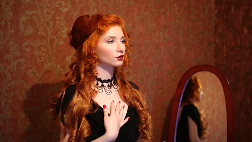 Portrait Of A Woman With Long Red Curly Hair In A Black And Red Dress And Choker On Her Neck