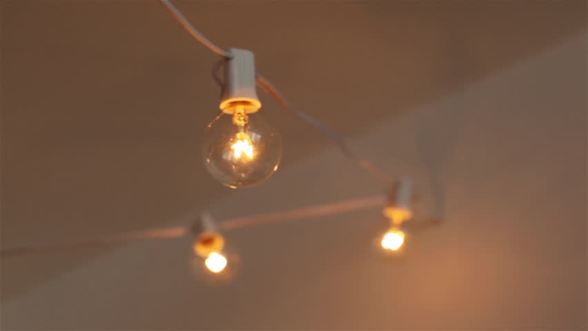 String Of Light Bulbs Hang From A White Ceiling