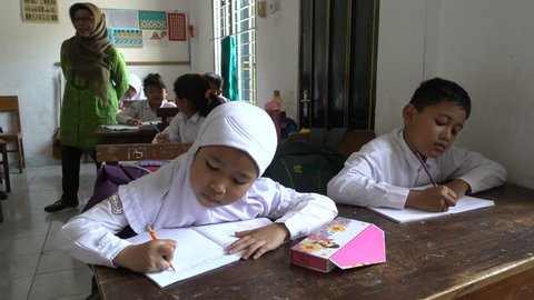 Muslim Schoolgirl Porn - Yogyakarta, indonesia - april 2017: veiled muslim elementary school girl  writes in classroom, indonesian kids study in yogyakarta