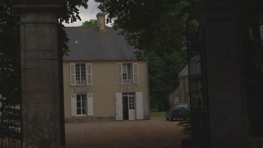View Of French Cottage House With Cars Passing Normandy France