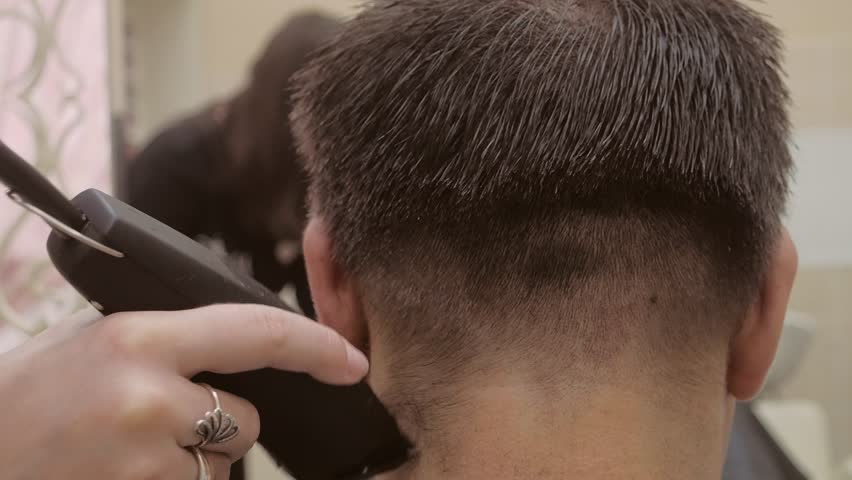 The hairdresser makes haircut to the man. male hairdresser hold in hand  comb and scissors closeup. trim the tips of the hair by scissors. manu0027s  (menu0027s) haircut with electric shaver.