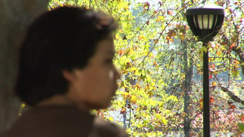 A tracking shot of a teenage boy walking down the sidewalk of a neighborhood.