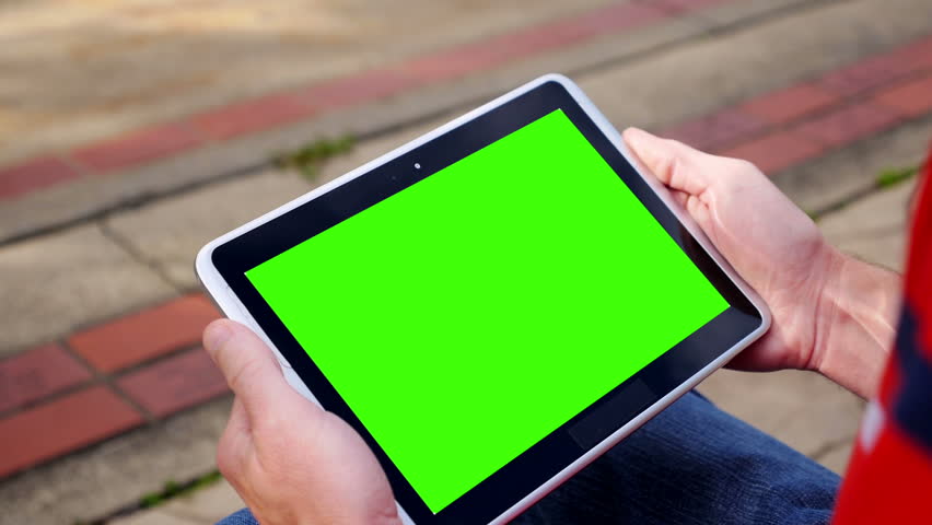 A man holds a blank tablet PC in landscape orientation with a green screen for
