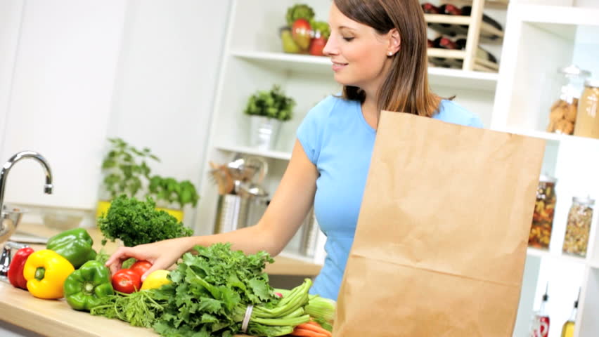 Young Woman Unpacking A Grocery Bag Full Of Healthy Organic Vegetables ...