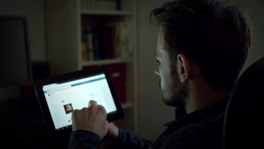 Dark Living Room At Night young man using facebook at night in the living room, with tablet Dark Living Room At Night young man using facebook at night in the living room, with tablet