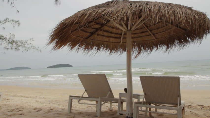 Beautiful Tropical Beach Palm Tree Sea Water Umbrella And Sunbed Two White Sun Loungers Site Under A Palm Leaf Parasol Umbrella While The Waves Roll Into